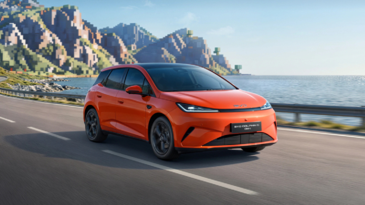 BYD Dolphin G DM-i híbrido plug-in na cor laranja em estrada costeira com montanhas e mar ao fundo