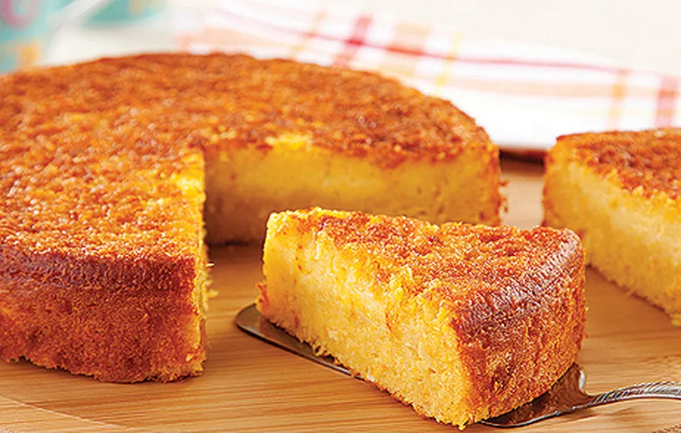 Bolo de milho cremoso irresistível sem farinha: praticidade no liquidificador 7 Bolo de milho dourado, cremoso, com fatia cortada sobre espátula em superfície de madeira