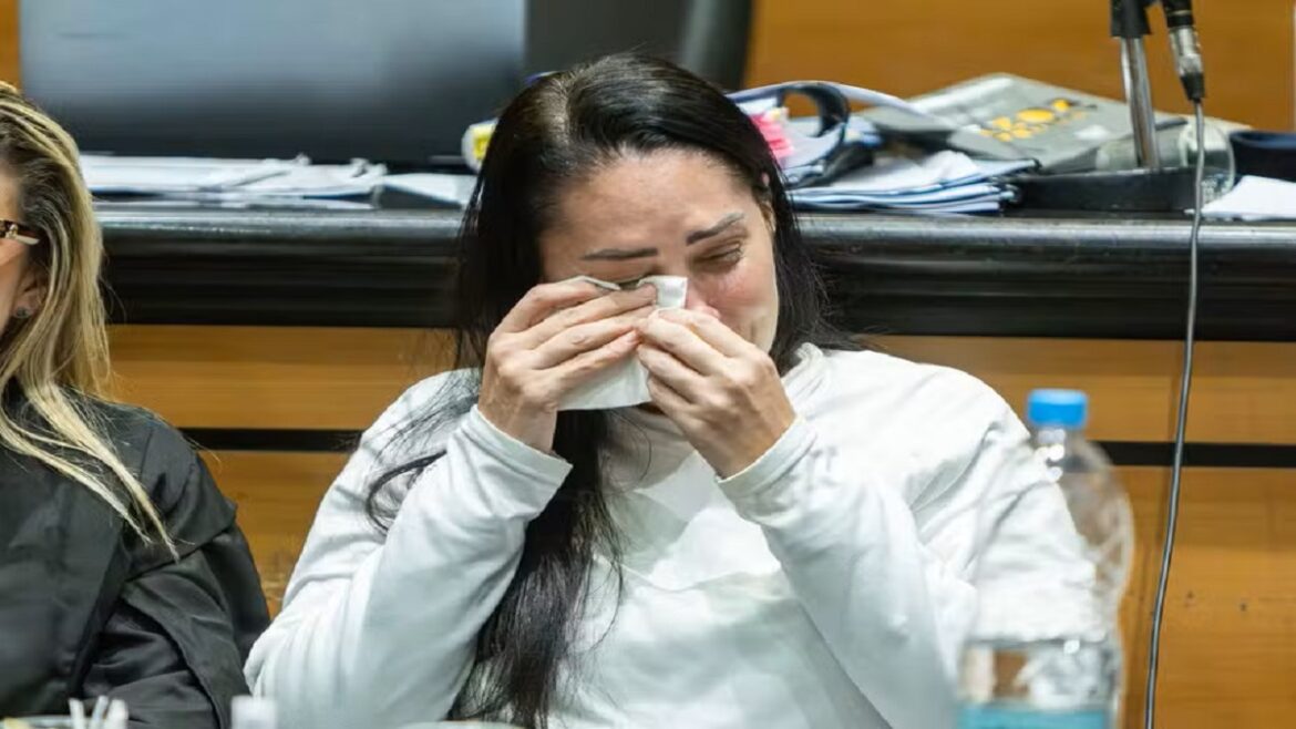 Monique Medeiros enxuga lágrimas com lenço de papel durante júri no Rio de Janeiro, trajando blusa branca