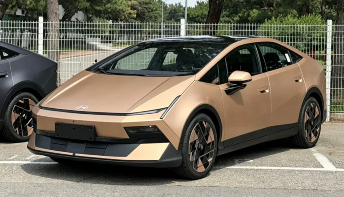 Hyundai Ioniq V bronze dourado com teto preto, rodas aerodinâmicas e design fastback em estacionamento