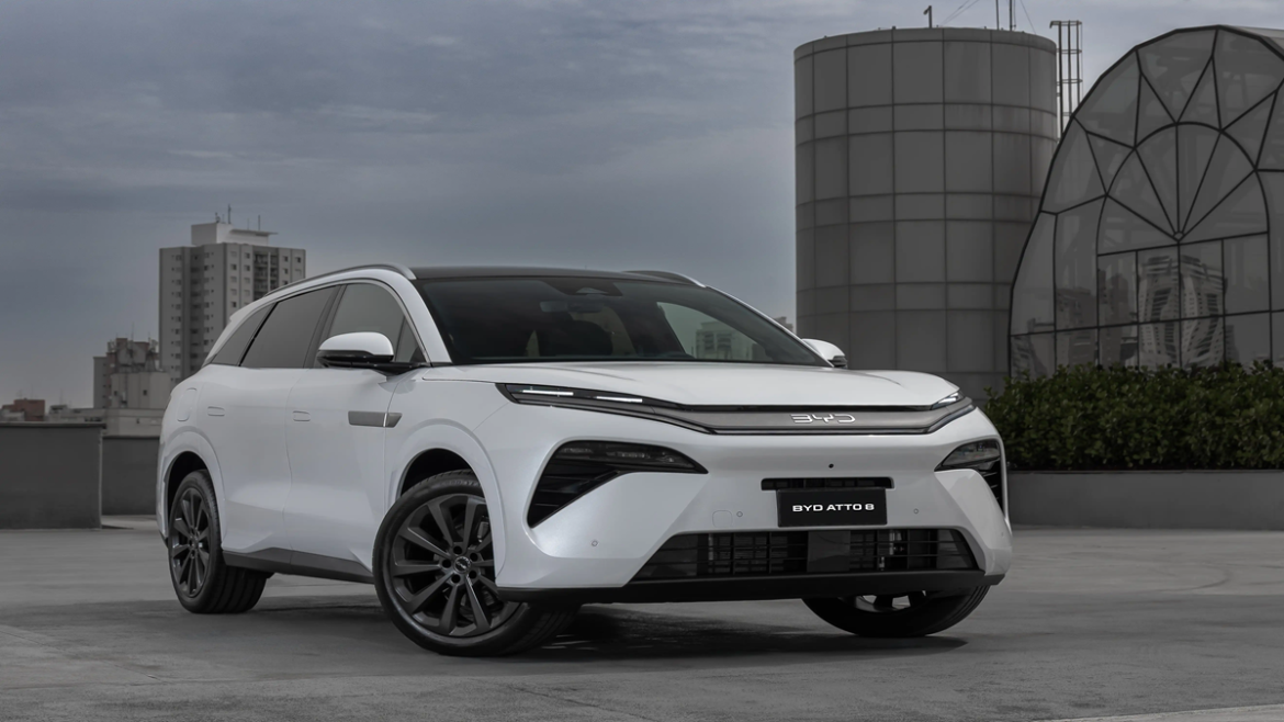 SUV BYD branco modelo Atto 8 estacionado em ambiente urbano com prédios ao fundo