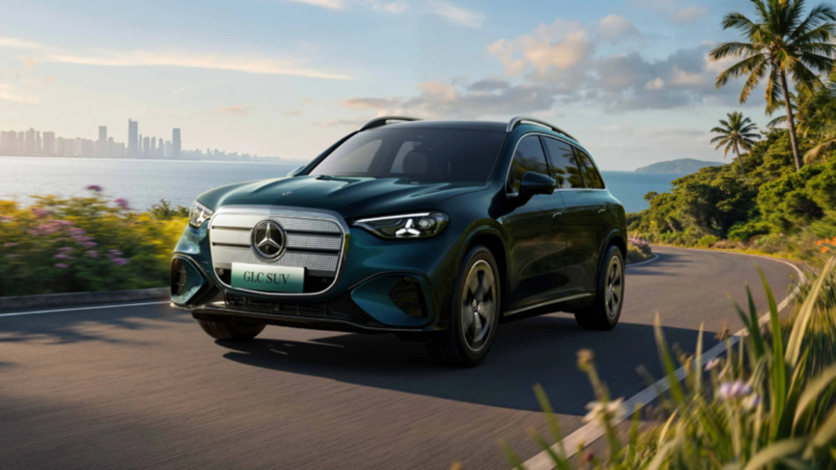 SUV Mercedes-Benz GLC azul escuro em estrada costeira com palmeiras e cidade ao fundo