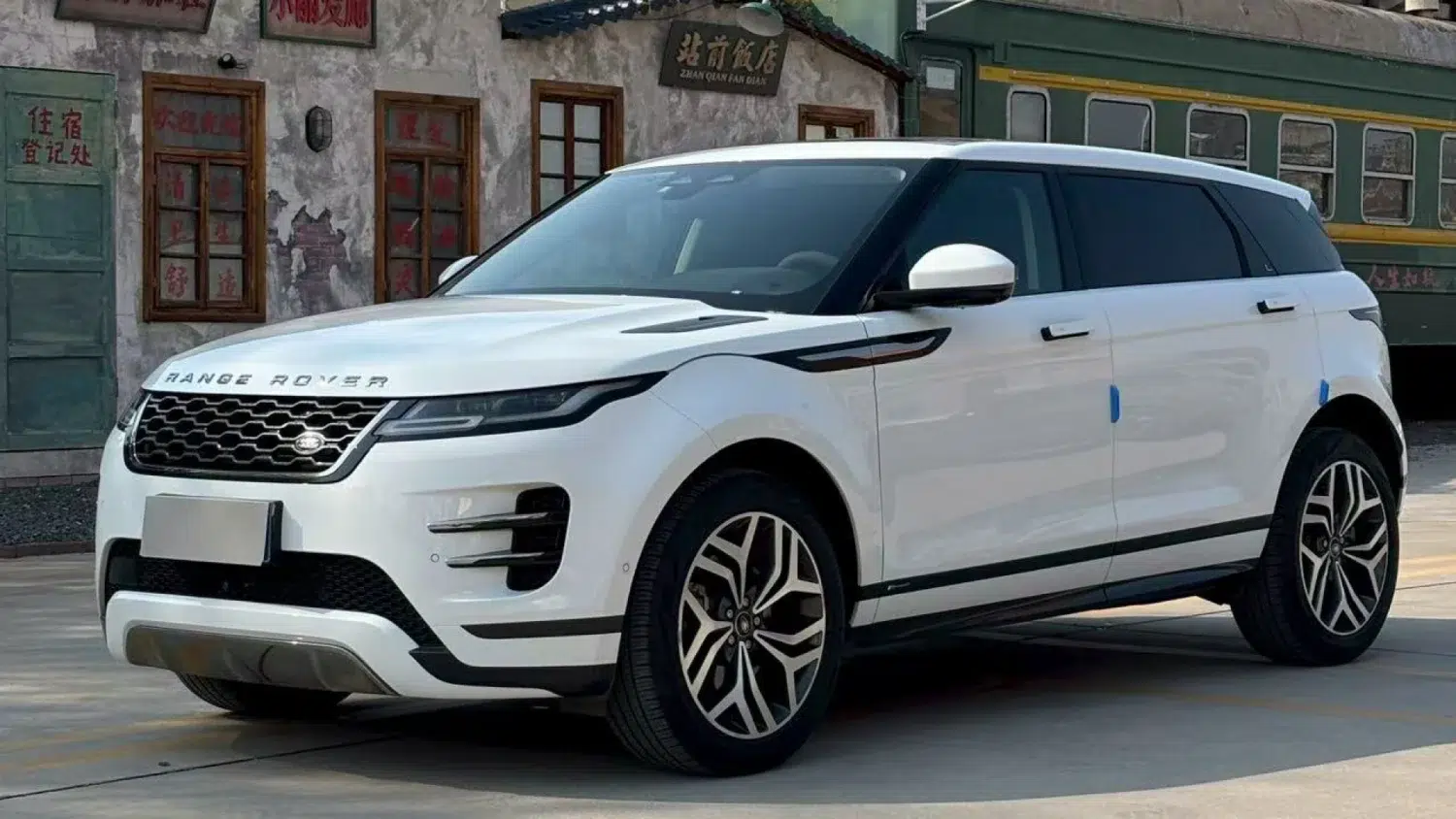 O preço do novo Range Rover Evoque L caiu 33.945 dólares na China 6 Range Rover Evoque L branco estacionado em frente a fachadas tradicionais chinesas com letreiros em mandarim