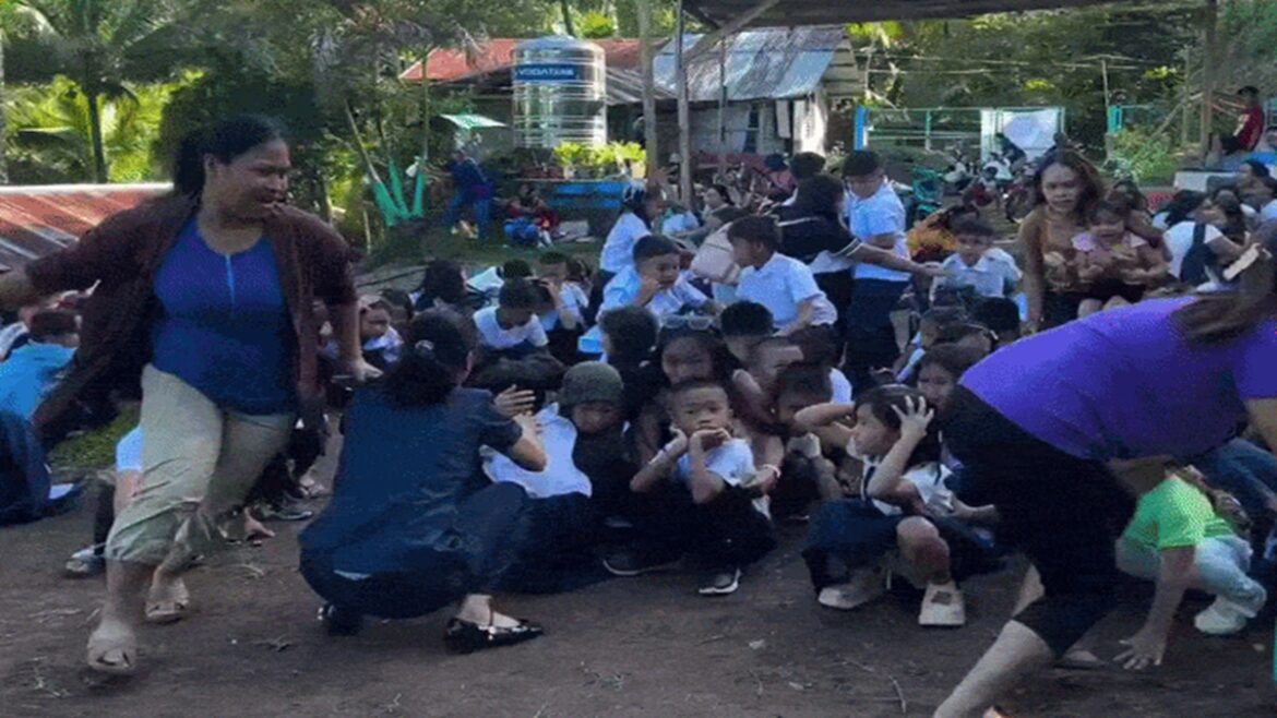 Professores auxiliam crianças uniformizadas agachadas com as mãos na cabeça em área externa de escola