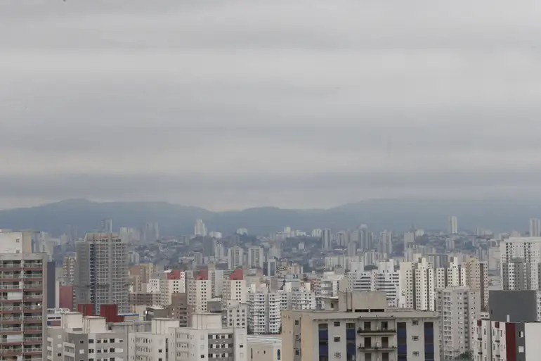 Feriado de 9 de julho suspende rodízio e fecha bancos, Correios e INSS em SP nesta quinta 6 Vista panorâmica de prédios residenciais e comerciais altos com céu cinza nublado ao fundo
