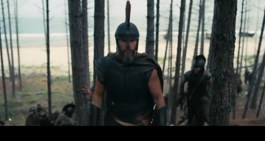 A Odisseia, novo épico de Christopher Nolan, bate recorde no Rotten Tomatoes e estreia nesta quinta (16) 6 Homem barbudo com elmo penacho e armadura caminha à frente de soldados em floresta junto ao mar
