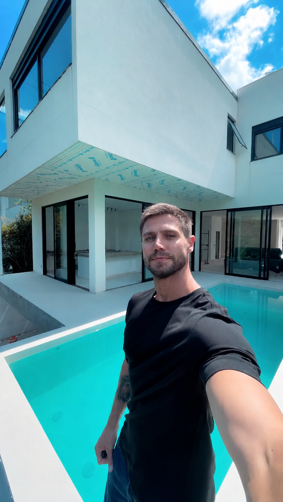 Adeus ao sonho: Jonas Sulzbach descarta morar na mansão de 4 suítes que construiu com Mari Gonzalez 6 Homem jovem de barba curta, camiseta preta, faz selfie ao lado de piscina em casa contemporânea branca
