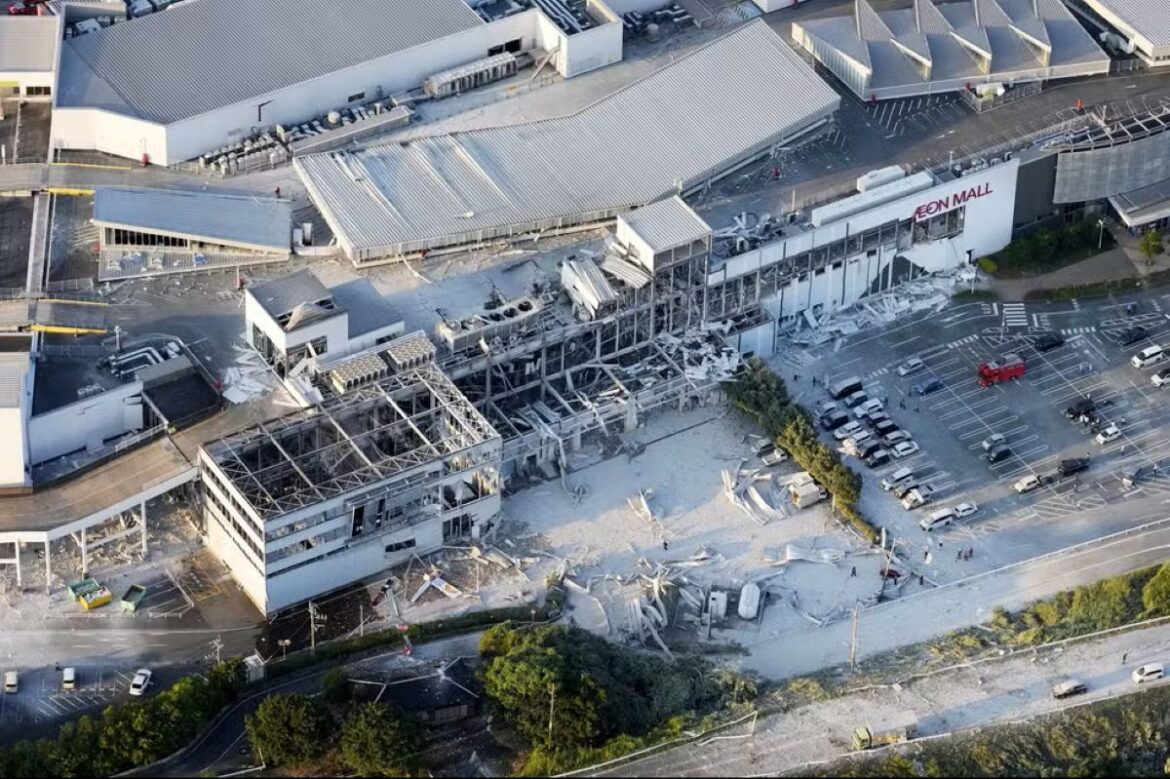 Visão aérea do Aeon Mall devastado, com parte do prédio destruído e escombros espalhados pelo chão