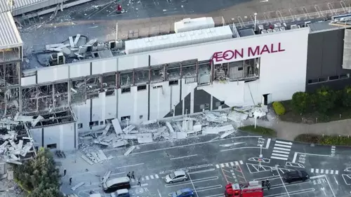 Terremoto de magnitude 7,1 atinge sul do Japão: mais de 150 mil pessoas vão para abrigos 6 Fachada do Aeon Mall parcialmente destruída, escombros caídos, viaturas e destroços no estacionamento